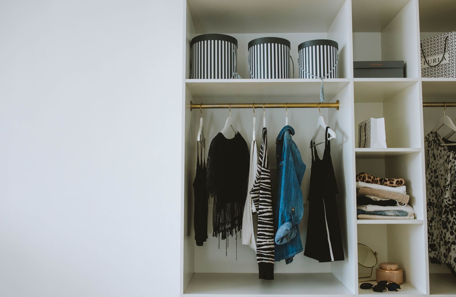 A tidy open wardrobe with folded knits, hangers and storage boxes.