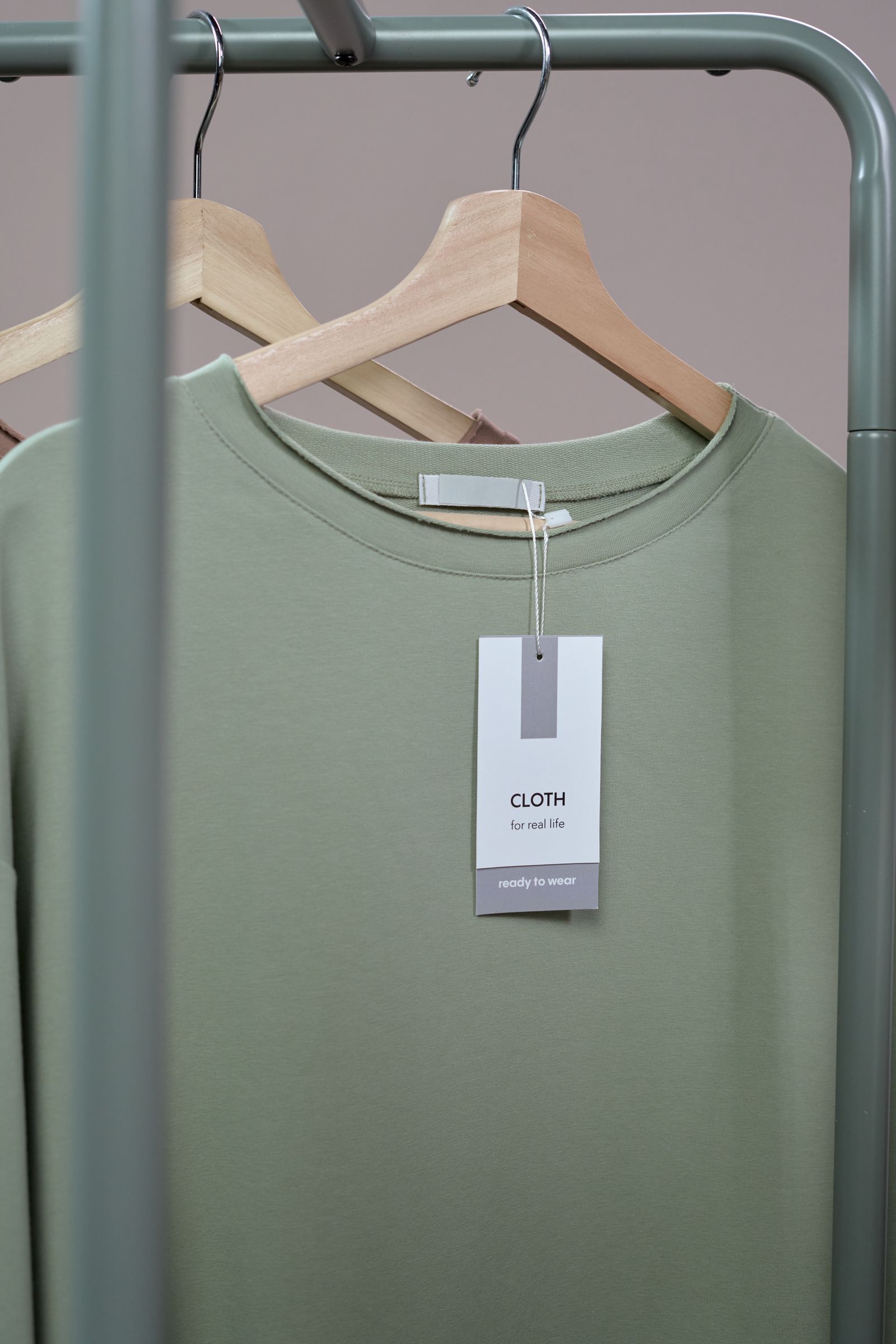 A plain t-shirt with a paper label hanging on a wooden hanger.