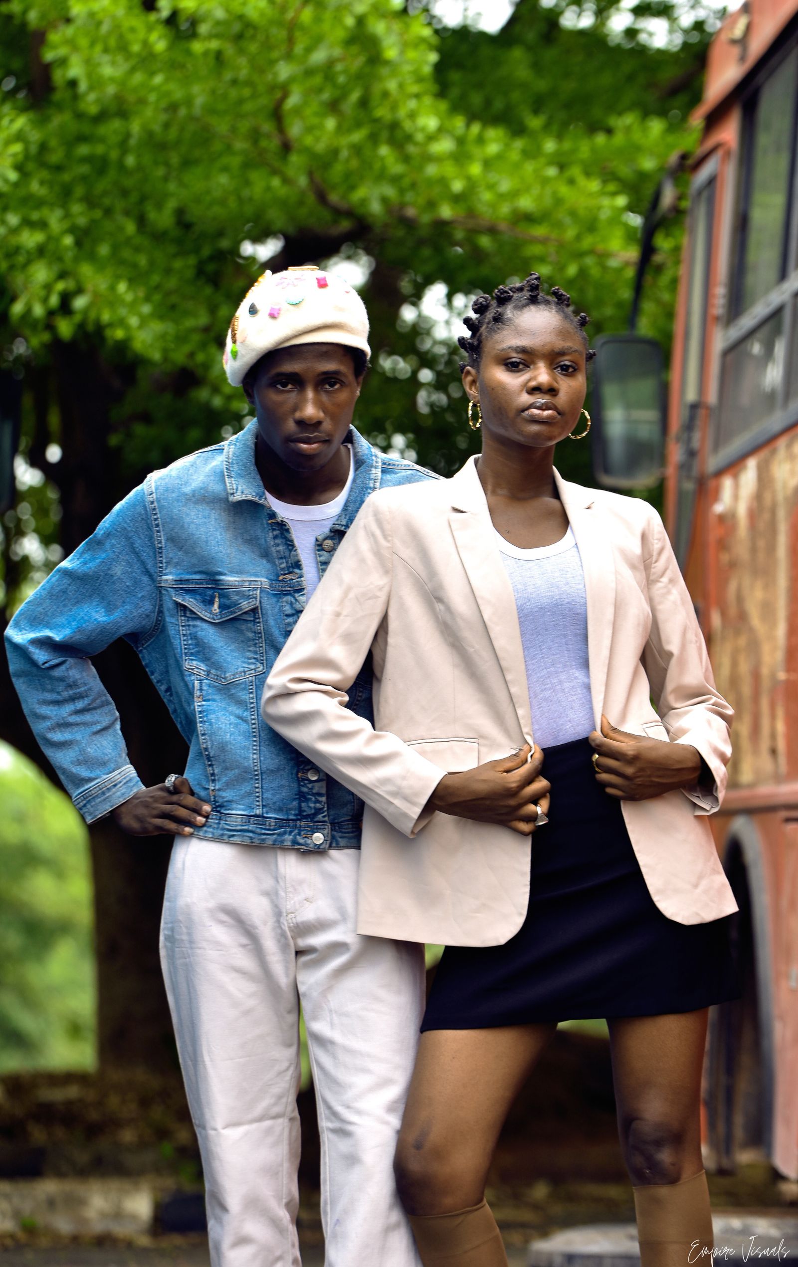 Two people in tailored jackets posing on a street.