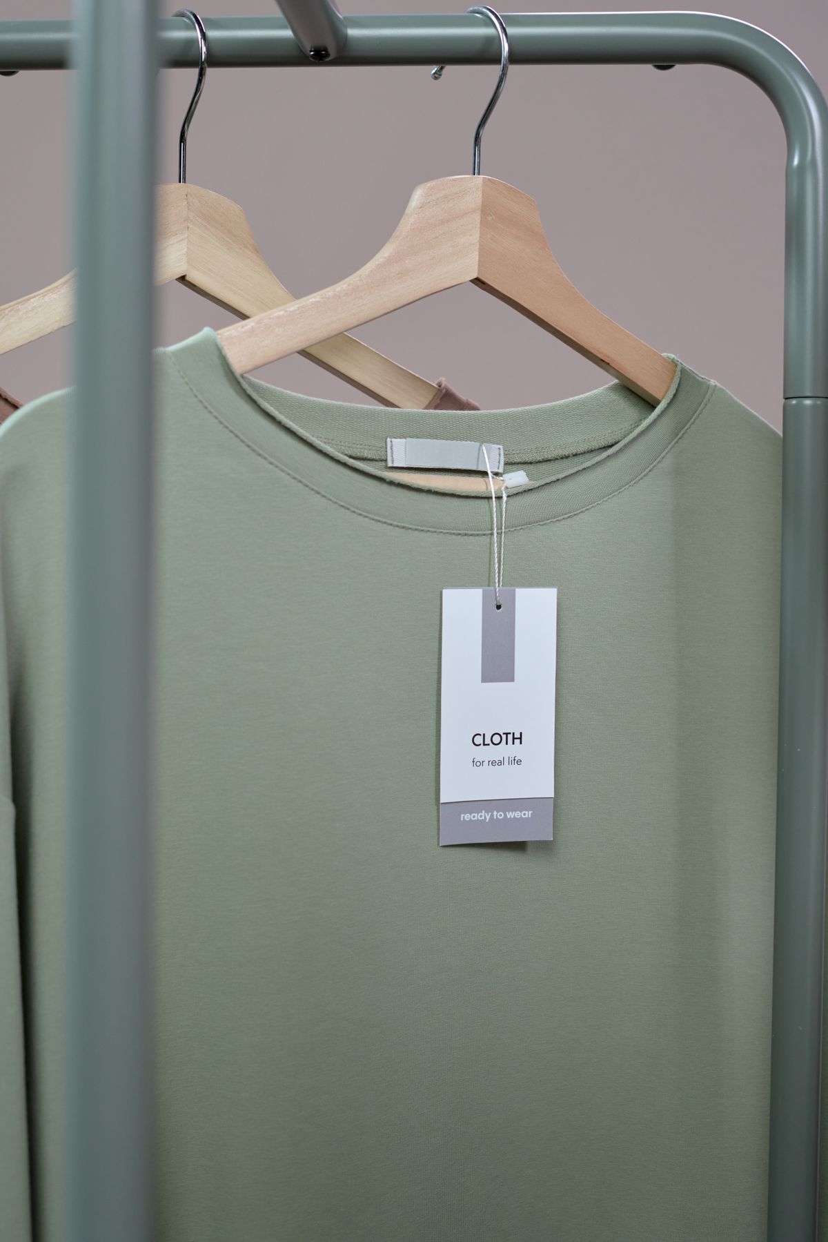 A plain t-shirt with a paper label hanging on a wooden hanger.